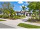 Elegant home featuring a brick-paved driveway, lush landscaping, and stately palm trees at 3519 Founders Club Dr, Sarasota, FL 34240