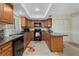 The kitchen features warm wood cabinetry and black appliances at 3740 Pinecone Ct # 163, Sarasota, FL 34238
