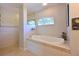 Bright bathroom featuring a tiled tub, and a shower room with elegant beige tile surround at 4412 Wolf Ridge Xing, Parrish, FL 34219
