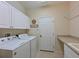 Laundry room featuring white cabinetry, a washer, a dryer, a utility sink and a door at 4412 Wolf Ridge Xing, Parrish, FL 34219