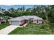 Inviting single-story home with a gray roof, attached garage, and lush green surroundings at 4673 Lummus St, North Port, FL 34286