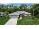 Inviting single-story home with a gray roof, attached garage, and lush green surroundings at 4673 Lummus St, North Port, FL 34286