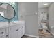 Modern bathroom with a round mirror, stylish blue tile backsplash, white vanity, and toilet at 4673 Lummus St, North Port, FL 34286