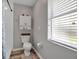 Cozy bathroom featuring a toilet with a white cabinet above, a window with blinds, and wood-look flooring at 4673 Lummus St, North Port, FL 34286