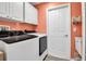 This laundry room includes washer, dryer, utility sink, a white storage cabinet, and an orange wall at 4673 Lummus St, North Port, FL 34286