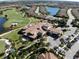 Aerial view of community clubhouse with manicured landscaping, palm trees, parking and a golf course nearby at 5019 Serata Dr, Lakewood Ranch, FL 34211
