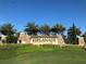 Stone monument sign for Esplanade Golf & Country Club with palm trees and manicured landscaping under a clear blue sky at 5019 Serata Dr, Lakewood Ranch, FL 34211