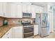 Modern kitchen with stainless steel appliances, including gas range, and granite countertops with tile backsplash at 5019 Serata Dr, Lakewood Ranch, FL 34211