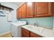 Laundry room featuring cherry cabinets, an ironing board, sink, and washer dryer at 5019 Serata Dr, Lakewood Ranch, FL 34211