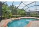 Screened-in pool featuring a decorative waterfall, lush landscaping and an umbrella covered seating area at 5019 Serata Dr, Lakewood Ranch, FL 34211
