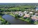 Aerial view of a property with a pool and solar panels, nestled near a lake amidst lush greenery at 5032 Timber Chase Way, Sarasota, FL 34238