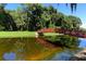 Picturesque red bridge over a tranquil pond, surrounded by greenery, offering a serene walking path at 5032 Timber Chase Way, Sarasota, FL 34238