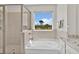 Bright primary bathroom featuring a separate glass enclosed shower and soaking tub with nature views at 5715 Woodland Sage Dr, Sarasota, FL 34238