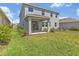 Back exterior view of a gray two-story home with a covered patio and green lawn at 5715 Woodland Sage Dr, Sarasota, FL 34238