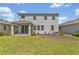 Back exterior view of a gray two-story home with a covered patio and green lawn at 5715 Woodland Sage Dr, Sarasota, FL 34238