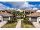 Beautiful condo exterior featuring lush landscaping, private garages, and a tiled roof against a bright sky at 5720 Palmer Cir # 103, Bradenton, FL 34211
