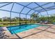 Backyard screened-in pool with a brick paver deck, lush landscaping, and serene pond views at 5749 Sunflower Cir, Sarasota, FL 34238