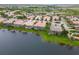 An aerial view of a neighborhood of houses with screened in pools bordering a serene lake at 6209 Erice St, Venice, FL 34293