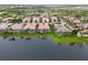 An aerial view of a neighborhood of houses with screened in pools bordering a serene lake at 6209 Erice St, Venice, FL 34293