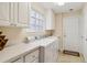A well-lit laundry room features a washer and dryer set, counter space, and white cabinets at 6209 Erice St, Venice, FL 34293