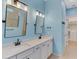 Bathroom featuring double sinks, white cabinets, and modern fixtures, adjacent to the walk-in closet at 6267 Crested Eagle Ln, Nokomis, FL 34275