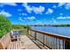 A waterfront wooden deck with seating provides a picturesque view of the serene water and lush greenery beyond at 6267 Midnight Pass Rd # 306, Sarasota, FL 34242