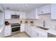 Bright kitchen featuring white cabinets, stainless steel appliances, and a decorative backsplash at 6267 Midnight Pass Rd # 306, Sarasota, FL 34242