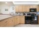 Well-equipped kitchen featuring wooden cabinets, laminate countertops, and black appliances with tile flooring at 6480 Midnight Pass Rd # 315, Sarasota, FL 34242
