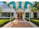 Welcoming entrance to The Varsity Club, featuring manicured landscaping, a brick walkway, and classic double doors at 7016 Lennox Pl, University Park, FL 34201