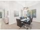 Elegant dining room with a glass-top table, modern chandelier, and a serene view of the outdoors at 7016 Lennox Pl, University Park, FL 34201