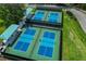 Aerial view showcases four well-maintained community pickleball courts, with shaded seating and vibrant blue surfaces at 7016 Lennox Pl, University Park, FL 34201
