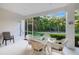 Cozy screened porch with wicker furniture, perfect for enjoying the outdoors, views of greenery and door to backyard at 7016 Lennox Pl, University Park, FL 34201