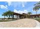 Elegant club entrance with a porte cochere, brick driveway, and lush tropical landscaping at 7158 Westhill Ct, Lakewood Ranch, FL 34202