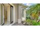 Inviting front entrance featuring a modern glass door and lush tropical landscaping around the home at 7158 Westhill Ct, Lakewood Ranch, FL 34202