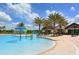 Beautiful community splash pool with palm trees and clubhouse in the background on a sunny day at 7158 Westhill Ct, Lakewood Ranch, FL 34202
