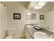 Bright bathroom with double vanity featuring a granite countertop, framed mirror, and decorative wall art at 7576 Plantation Cir, Bradenton, FL 34201