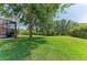 A beautifully landscaped backyard with a large grassy area, mature trees, and a view of the screened-in patio at 8136 Snowy Egret Pl, Bradenton, FL 34202