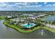 Aerial view showcasing the community clubhouse with a pool, lake, playground, and tennis court at 8936 Artisan Way, Sarasota, FL 34240