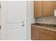 Mud room featuring granite countertops, wooden cabinetry, and a sleek white entry door at 8936 Artisan Way, Sarasota, FL 34240