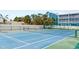 Outdoor tennis court surrounded by trees, landscaping and a fence, offering privacy at 901 Gulf S Dr # 14, Bradenton Beach, FL 34217