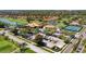 Aerial view of a golf community featuring a clubhouse, tennis courts, and scenic ponds at 4812 Sand Trap E Cir, Bradenton, FL 34203