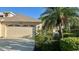 Single-story home with a two-car garage and lush landscaping, including a mature palm tree at 4812 Sand Trap E Cir, Bradenton, FL 34203