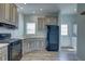 Bright kitchen with neutral cabinets, black appliances, wood grain floors, and access to the laundry room at 104 1St Ave, Venice, FL 34285