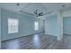 Light-filled living room with tray ceiling, fan, and stylish gray wood-look flooring at 104 1St Ave, Venice, FL 34285
