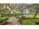 Lush backyard showcasing a serene lake view, mature trees, and a brick paver patio at 1085 Mallard Marsh Dr, Osprey, FL 34229