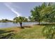 A tranquil backyard overlooking a serene lake, enhanced by lush greenery and mature trees at 12740 Del Corso Loop, Lakewood Ranch, FL 34211