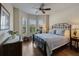 Relaxing bedroom features comfortable iron frame bed, hardwood floors, bright windows and tray ceiling detail at 12740 Del Corso Loop, Lakewood Ranch, FL 34211