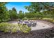 Circular brick fire pit with contemporary seating surrounded by lush greenery in outdoor living space at 12740 Del Corso Loop, Lakewood Ranch, FL 34211