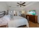 Cozy main bedroom with tray ceiling, hardwood floors, dresser with TV and view into ensuite bathroom at 12740 Del Corso Loop, Lakewood Ranch, FL 34211