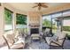 This sunroom features comfortable seating, a ceiling fan, and a fireplace with views of the lake at 12740 Del Corso Loop, Lakewood Ranch, FL 34211